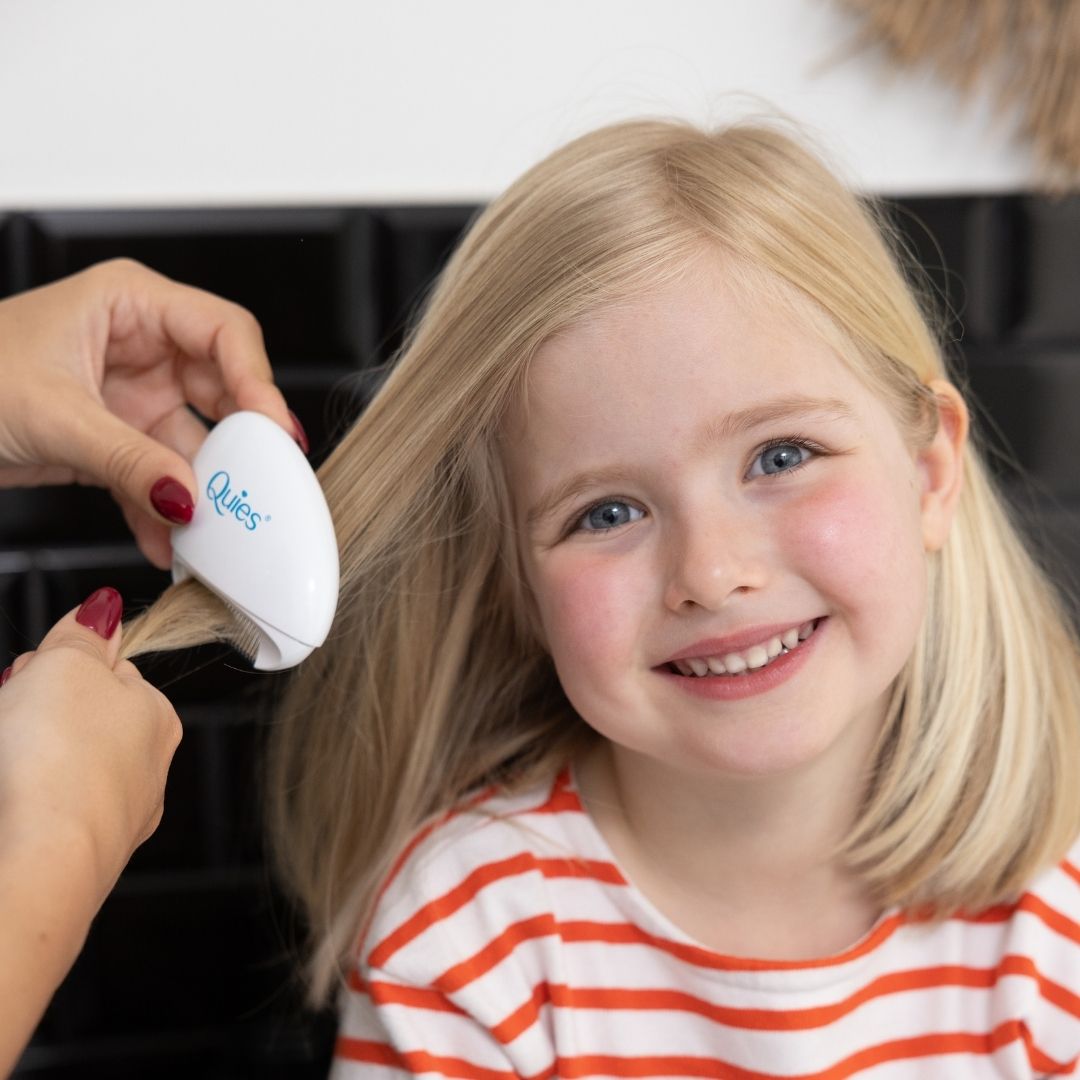 Mère passant le peigne électronique Quies dans les cheveux de sa fille pour éliminer les poux
