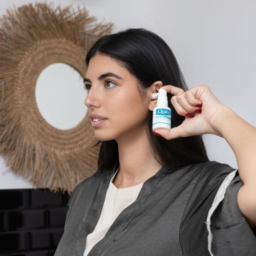 Femme utilisant le spray auriculaire Quies Doculyse dans son oreille
