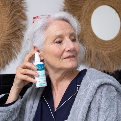 Texte alternatif : Femme utilisant le Docuspray Quies pour nettoyer ses oreilles dans la salle de bain