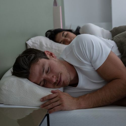 Homme dormant avec l'oreiller Quies Anti-Ronflement