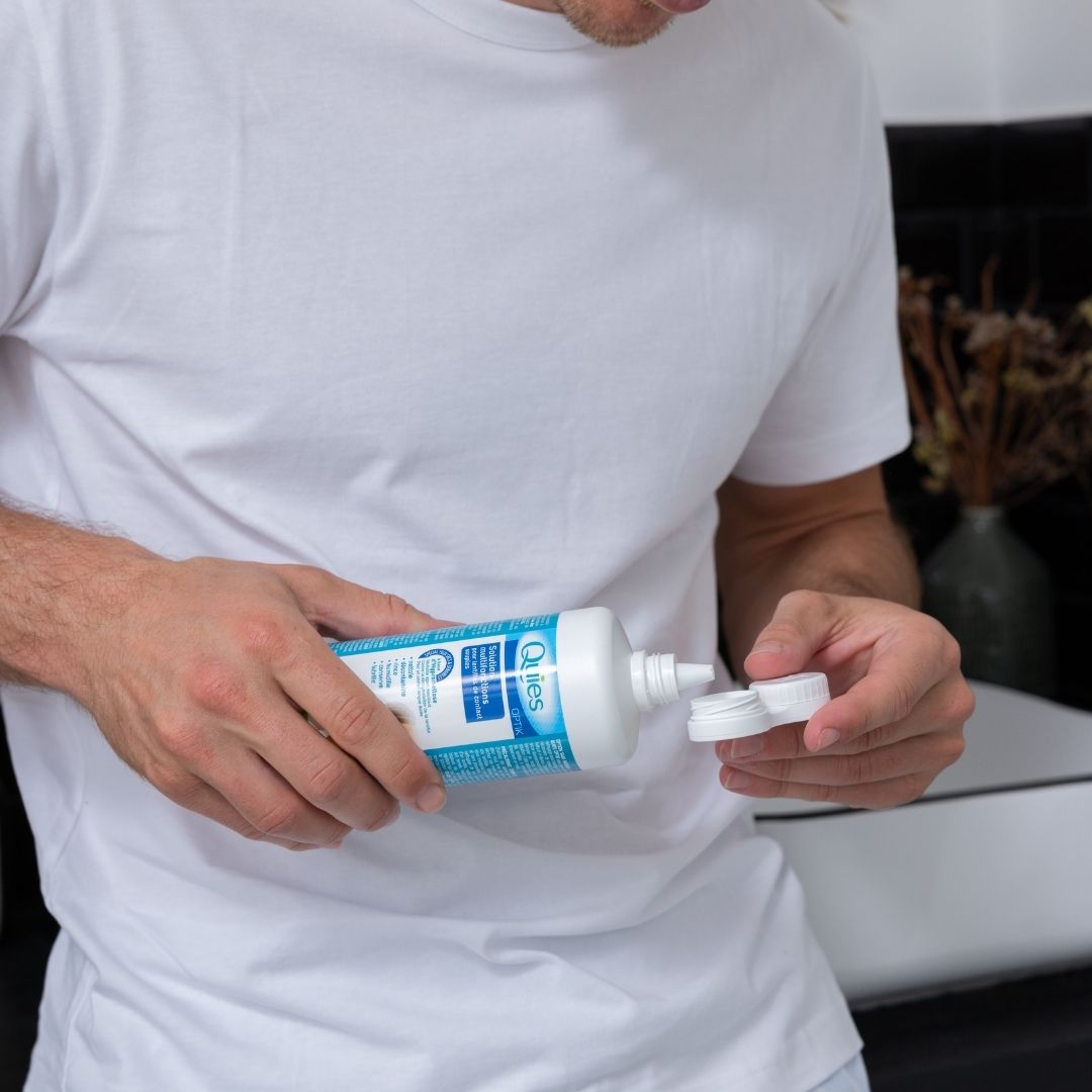 Homme remplissant l'étui à lentilles avec la solution multifonctions Quies