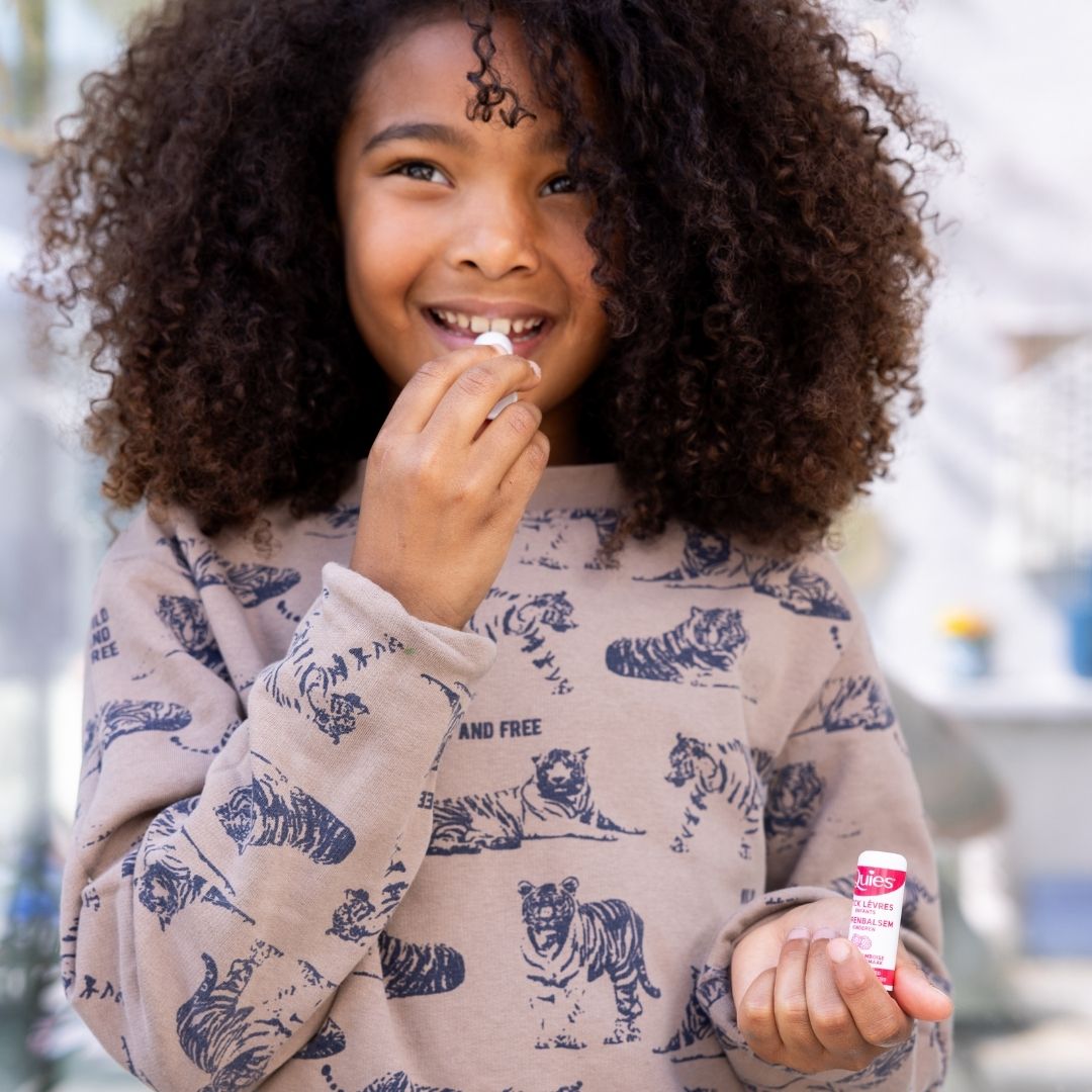 Petite fille appliquant un stick à lèvres Quies hydratant